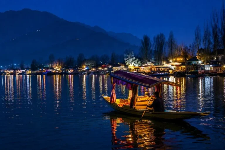 Romantic shikara ride on Dal Lake at night in Srinagar with glowing reflections and houseboats, perfect for a Kashmir honeymoon package 5 nights 6 days.