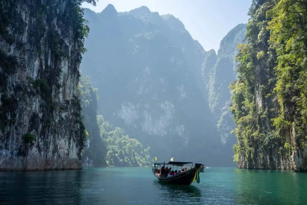Long-tail boat on Cheow Lan Lake surrounded by limestone cliffs in Thailand